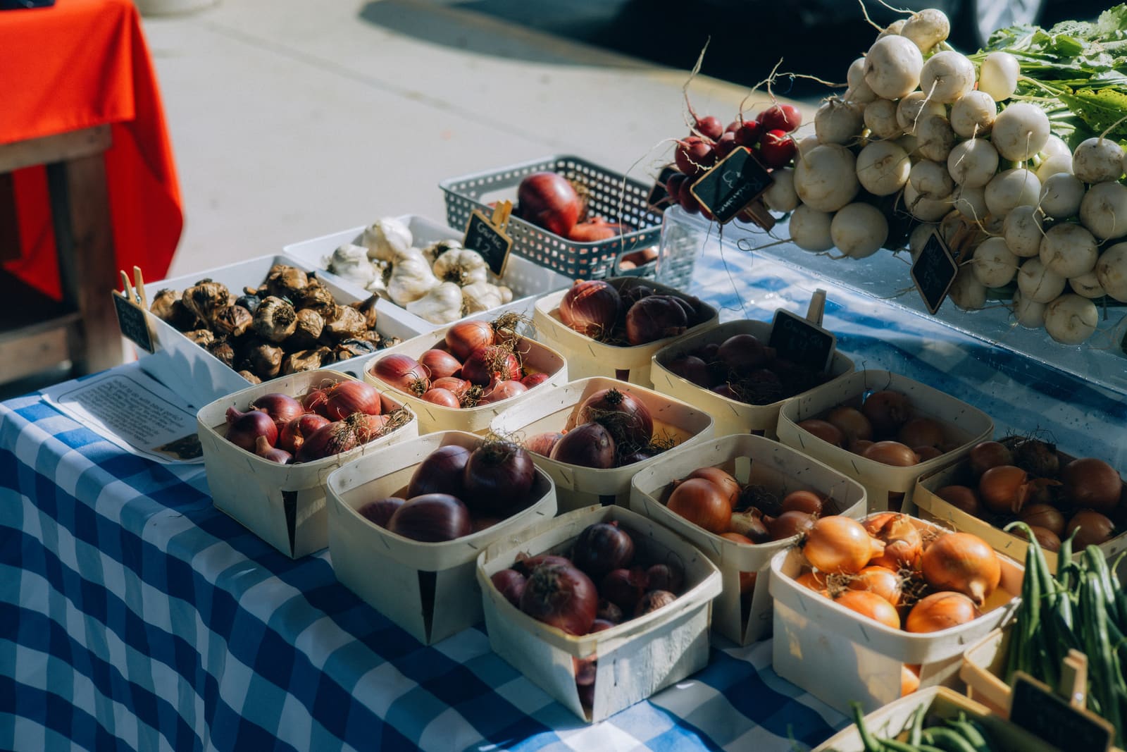 A sunlit farmers-market stall with baskets of fresh produce