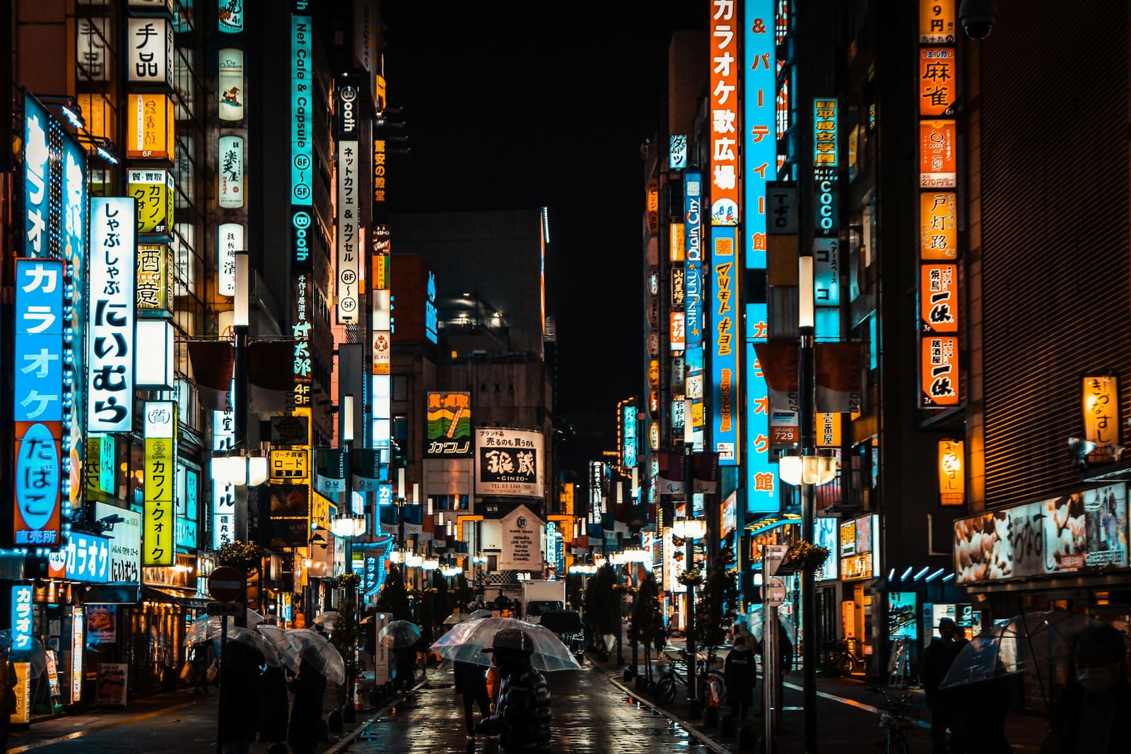 People walking a Tokyo street lit by shopfronts at night
