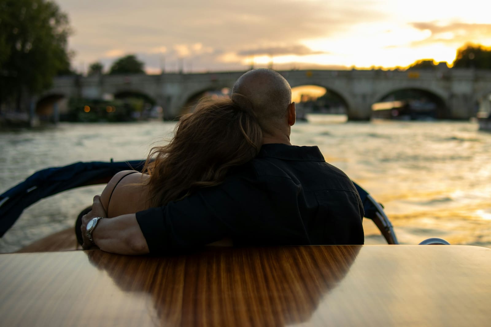 A couple sitting side by side on a boat in the evening light