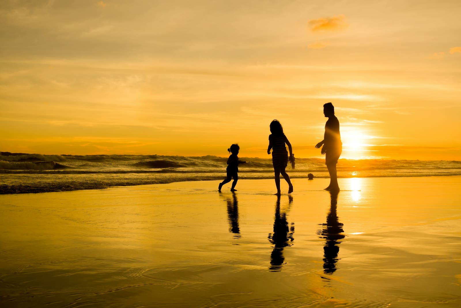 A family walking together along the shoreline at sunset