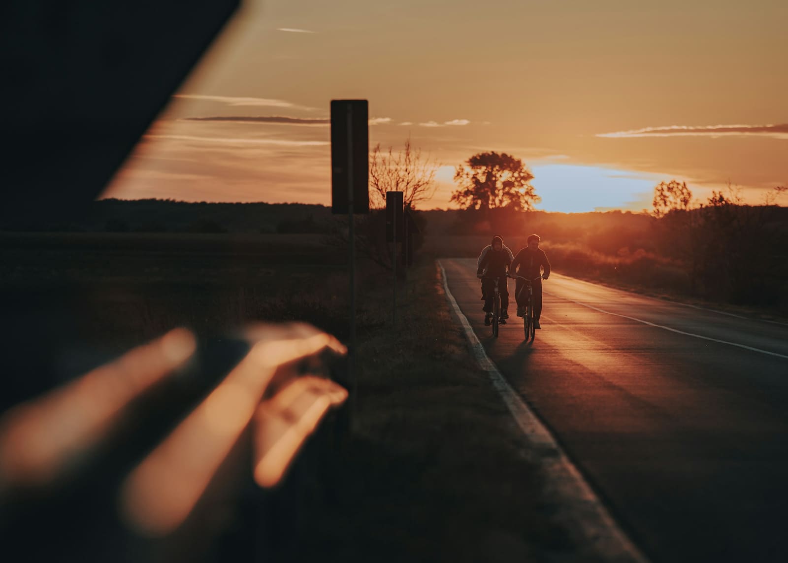 Two friends riding bikes down an open road at golden hour